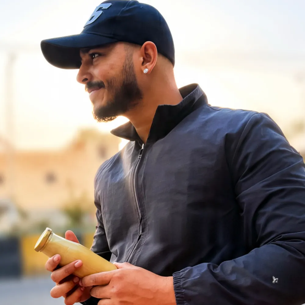 A Fruit Fresh co-founder holding a bottle of lassi in the morning sun